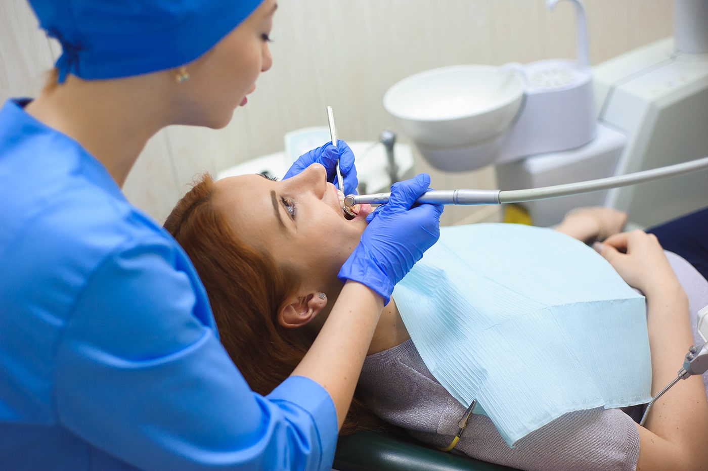 doctor-uniform-checking-up-female-patient-s-teeth-dental-clinic-min